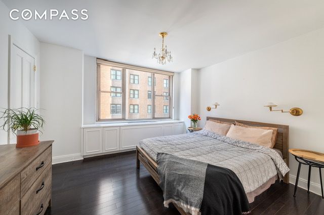 bedroom with dark wood finished floors, baseboards, and an inviting chandelier