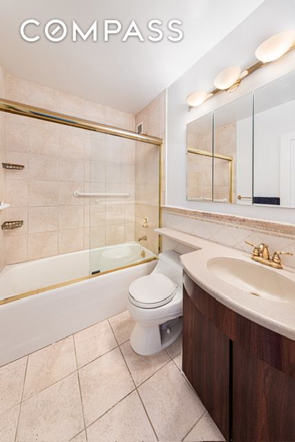 137 E 36th St Unit 6G, New York City, NY 10016 - full bath featuring vanity, toilet, tile patterned floors, and combined bath / shower with glass door