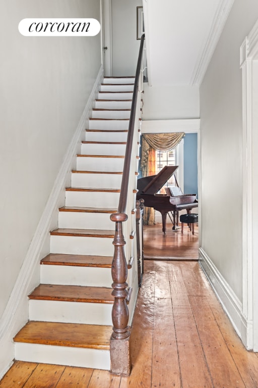 stairs featuring crown molding, baseboards, and wood finished floors