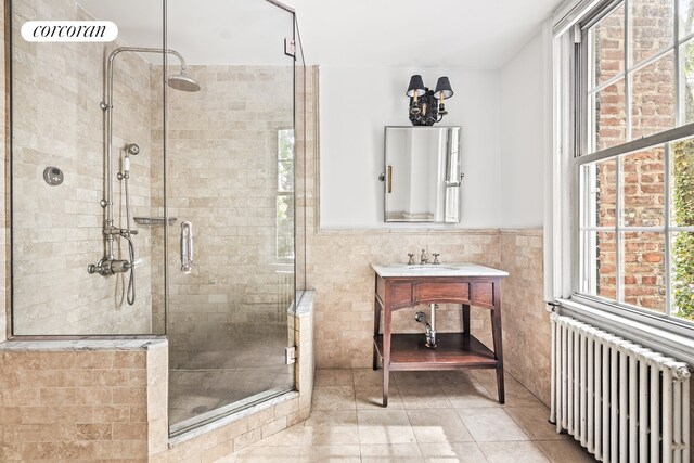 bathroom featuring a stall shower, a wainscoted wall, tile walls, and radiator heating unit