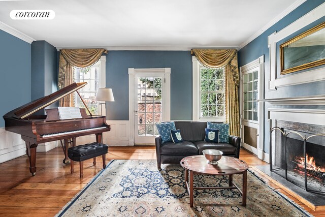 living area featuring light wood-type flooring, visible vents, crown molding, and a lit fireplace