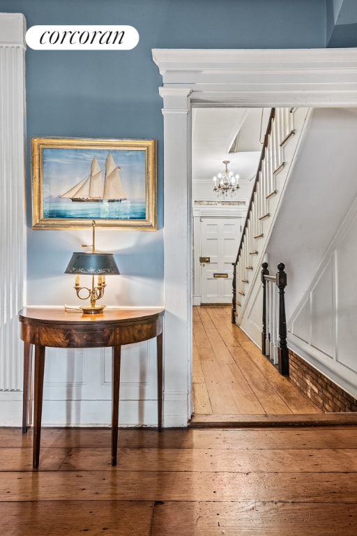 hallway with a chandelier, stairway, and wood finished floors