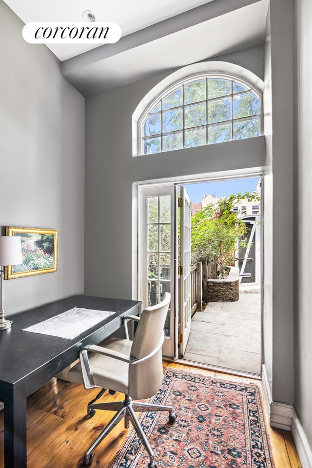 home office featuring a high ceiling, baseboards, and wood finished floors