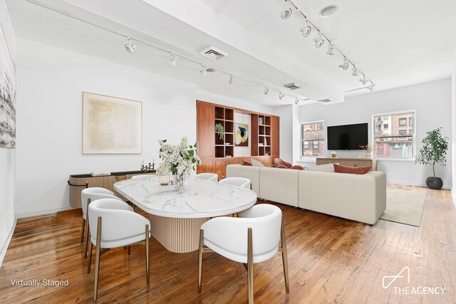 dining space featuring hardwood / wood-style flooring, baseboards, visible vents, and rail lighting