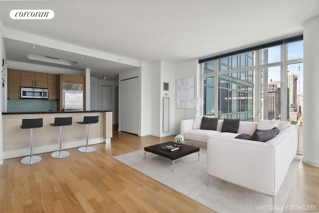 living room featuring light wood-type flooring and floor to ceiling windows