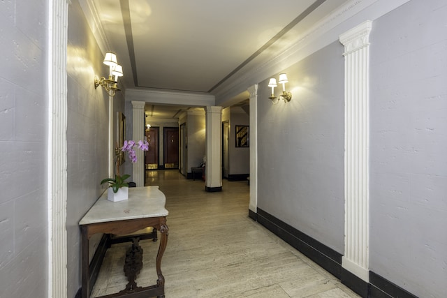 corridor with baseboards, decorative columns, crown molding, and light wood-style flooring