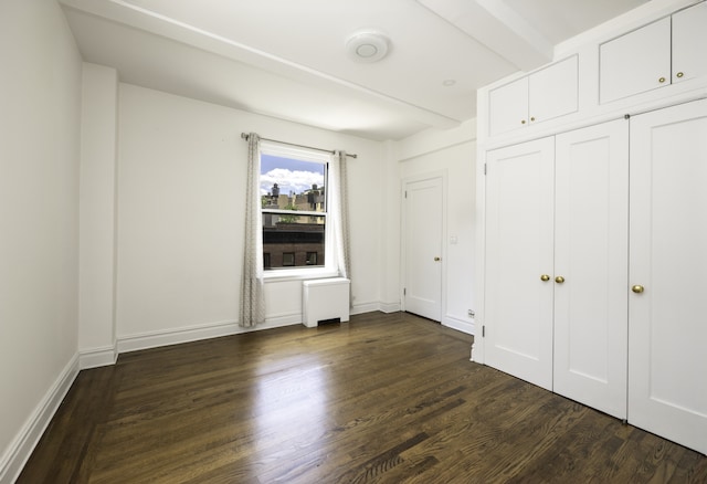 unfurnished bedroom with baseboards, dark wood-style flooring, and beam ceiling