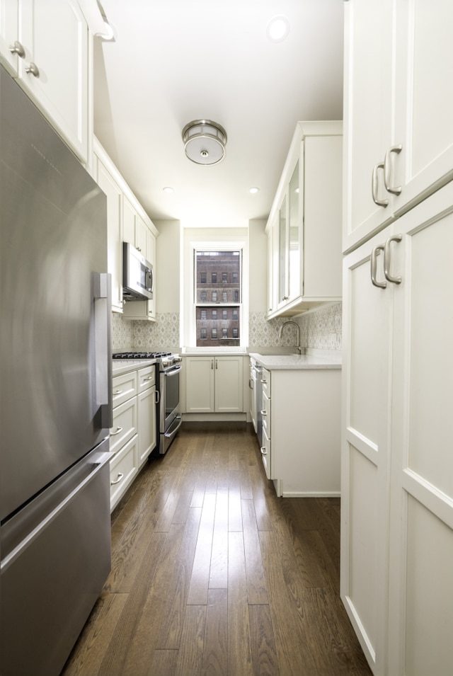 kitchen with decorative backsplash, dark wood-style flooring, glass insert cabinets, and appliances with stainless steel finishes