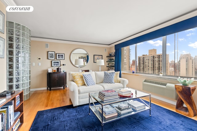 living area featuring wood finished floors, baseboards, a wall mounted AC, ornamental molding, and a view of city