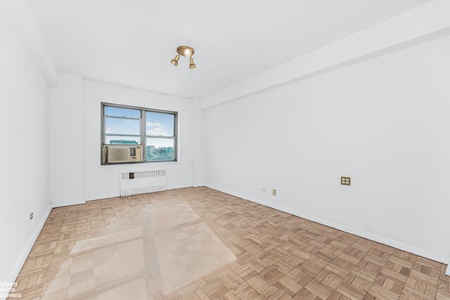 unfurnished room featuring light wood-type flooring, radiator heating unit, and a healthy amount of sunlight