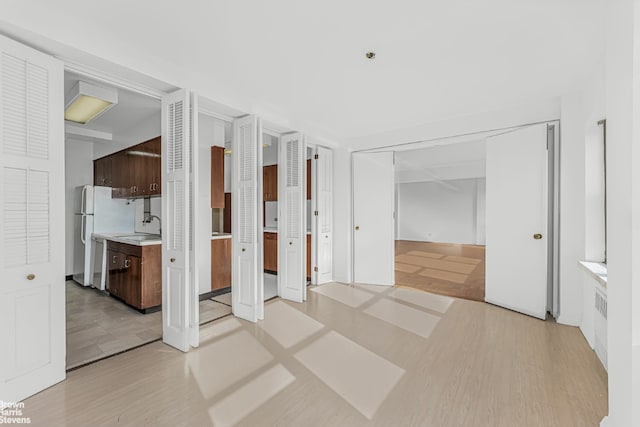 unfurnished bedroom featuring ensuite bath, light hardwood / wood-style flooring, white fridge, and sink