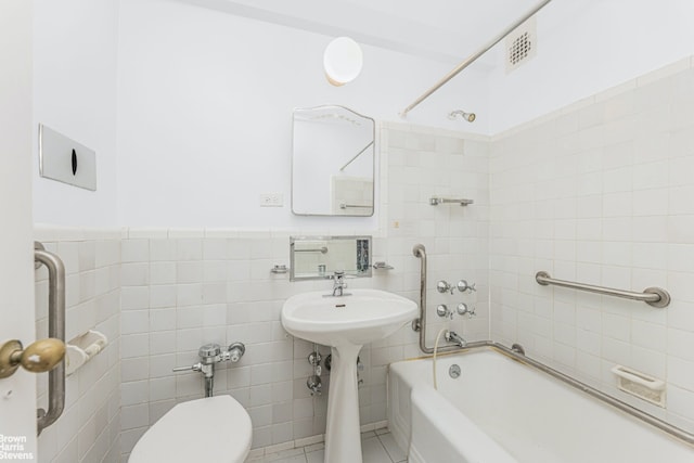 bathroom with toilet, tile walls, and tiled shower / bath combo