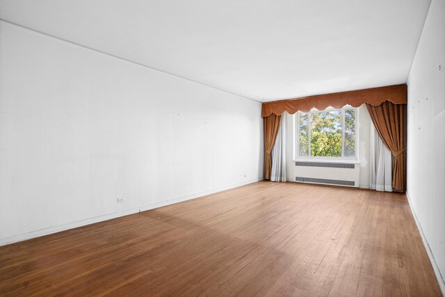 empty room featuring light wood-type flooring and radiator heating unit