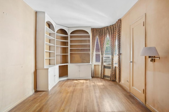 spare room featuring radiator, baseboards, and light wood finished floors