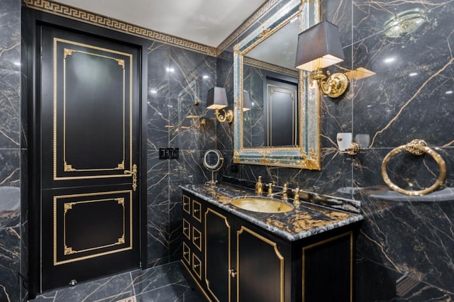 bathroom with marble finish floor, vanity, and tile walls