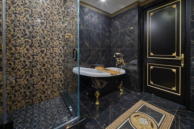 bathroom with marble finish floor, a freestanding tub, tile walls, and a shower stall