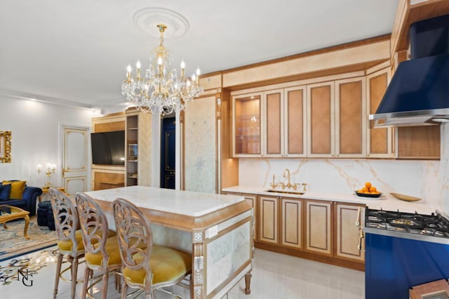 kitchen with light countertops, a chandelier, hanging light fixtures, a sink, and wall chimney exhaust hood