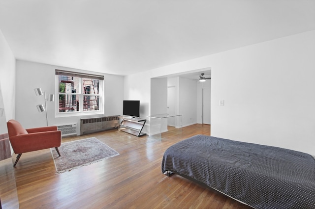 bedroom featuring a wall mounted AC, hardwood / wood-style floors, and radiator heating unit