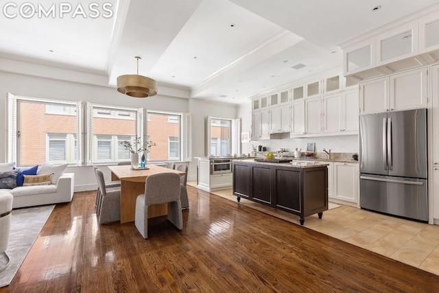 kitchen featuring white cabinets, stainless steel fridge, backsplash, a center island, and light hardwood / wood-style floors