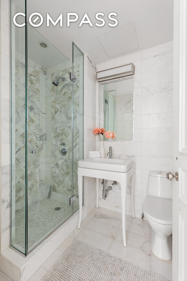 full bath featuring tile walls, toilet, and a marble finish shower