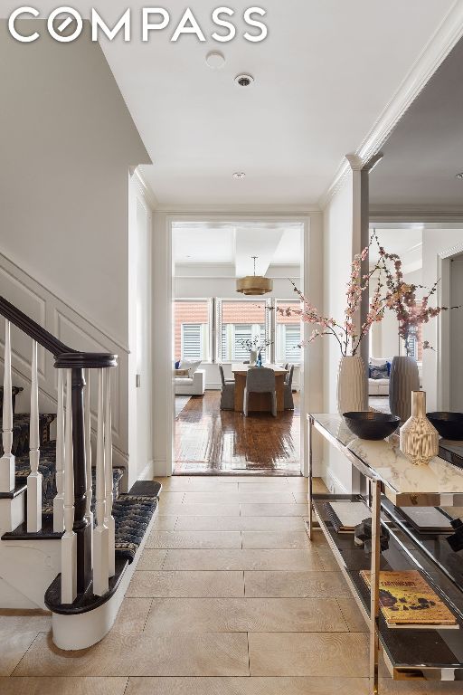 corridor with ornamental molding and hardwood / wood-style floors