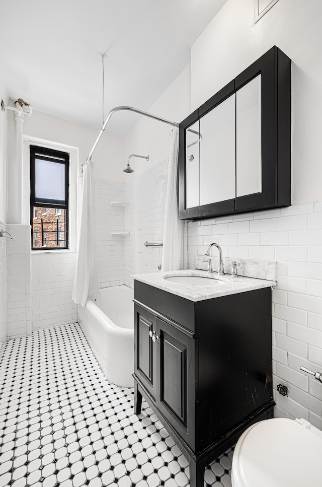 full bath featuring tile walls, toilet, shower / bath combo with shower curtain, vanity, and a wainscoted wall