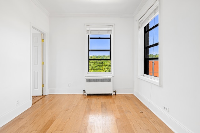 unfurnished room featuring radiator heating unit, baseboards, light wood-style flooring, and crown molding