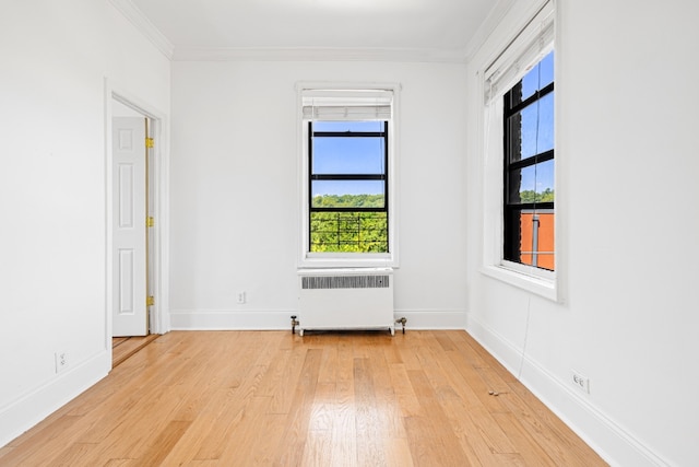 empty room with light hardwood / wood-style floors, radiator, and ornamental molding