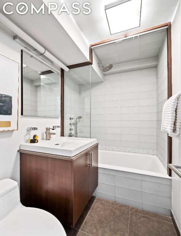 full bathroom with toilet, tile patterned flooring, tiled shower / bath, and vanity