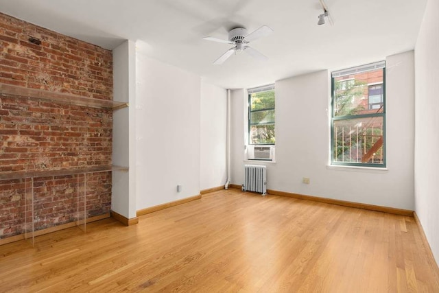 unfurnished room featuring rail lighting, ceiling fan, cooling unit, light wood-type flooring, and radiator