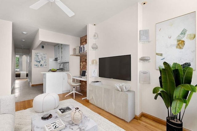 living area featuring light wood-style floors, baseboards, visible vents, and a ceiling fan