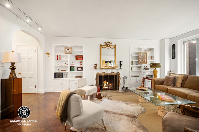 living room with built in shelves and dark parquet floors