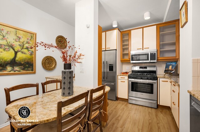 kitchen featuring tasteful backsplash, light stone counters, stainless steel appliances, and light hardwood / wood-style floors