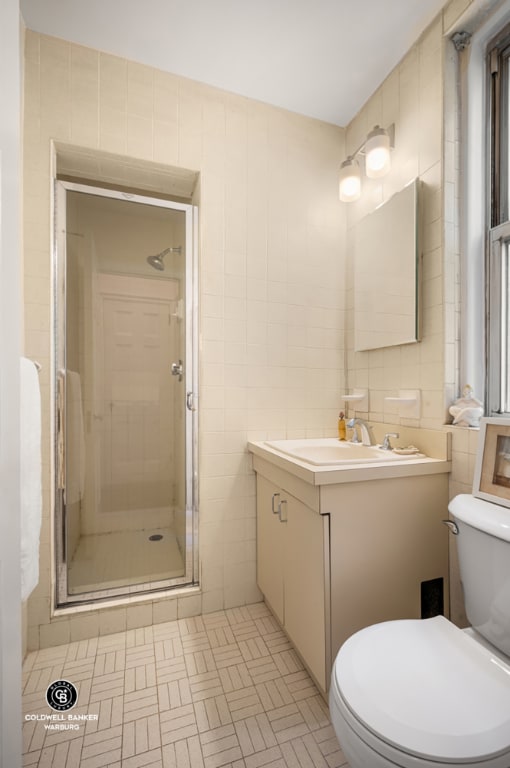 bathroom featuring toilet, tile walls, and a shower with shower door