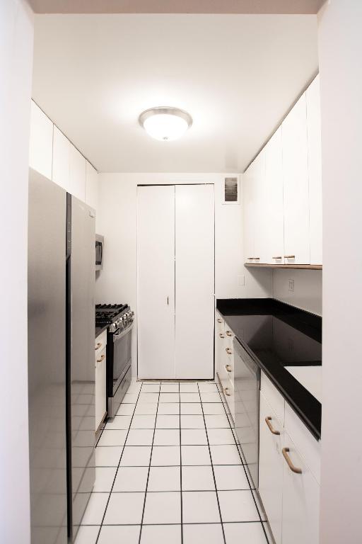 kitchen featuring appliances with stainless steel finishes, white cabinetry, and light tile patterned flooring