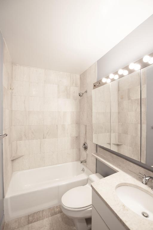 full bathroom featuring tiled shower / bath combo, vanity, and toilet