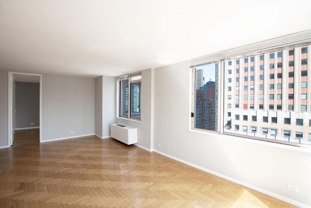 spare room featuring radiator and parquet floors