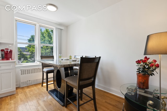 dining room featuring radiator, light wood-style floors, and baseboards