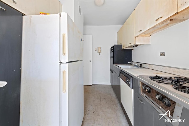 kitchen featuring dishwasher, white fridge, sink, stovetop, and cream cabinets