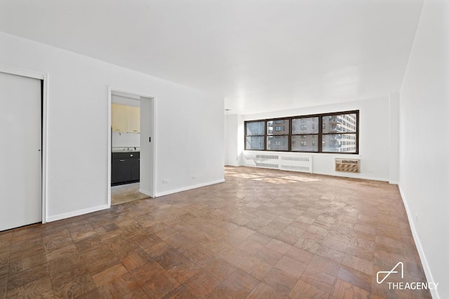 unfurnished room featuring radiator and baseboards