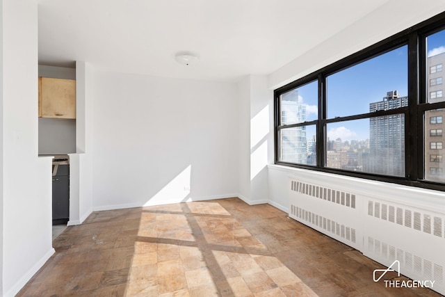 185 W End Ave Unit 25H, New York City, NY 10023 - unfurnished room with radiator heating unit, plenty of natural light, stone finish flooring, and a city view