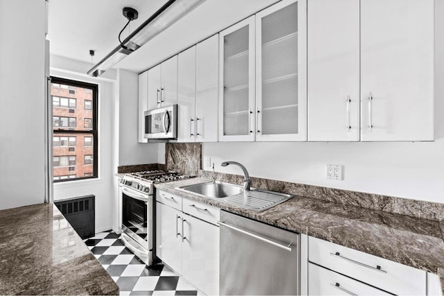 kitchen featuring sink, white cabinetry, appliances with stainless steel finishes, and dark stone counters