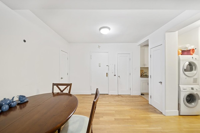 dining space featuring stacked washer and dryer, light wood-style flooring, and baseboards