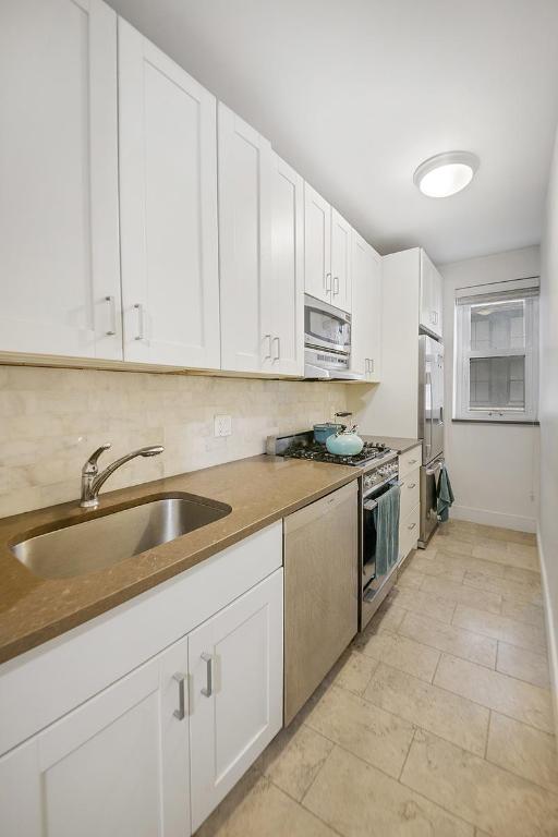 kitchen with white cabinetry, appliances with stainless steel finishes, sink, and decorative backsplash