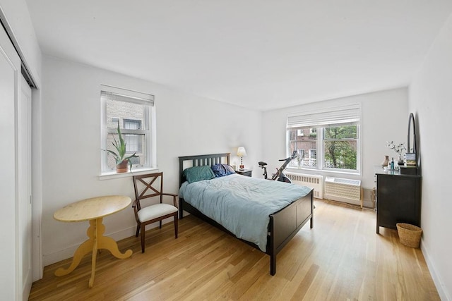 bedroom featuring multiple windows, radiator, a closet, and light hardwood / wood-style flooring