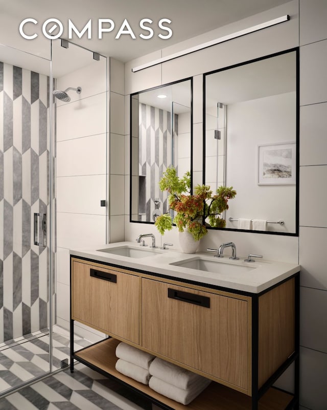 bathroom with a sink, a stall shower, double vanity, and tile walls