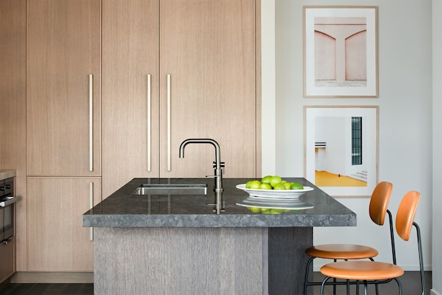 kitchen featuring a breakfast bar area, light brown cabinets, and a sink