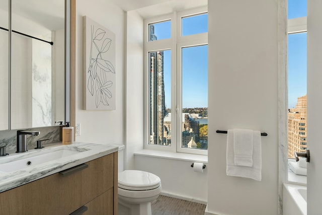 bathroom with toilet, vanity, and baseboards