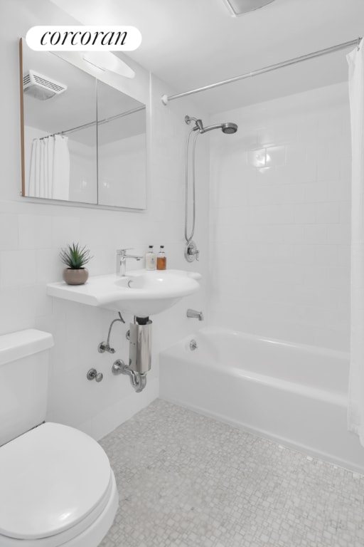 bathroom with shower / bath combo, tile walls, and toilet