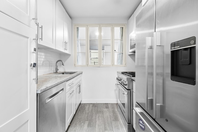 kitchen with white cabinets, decorative backsplash, appliances with stainless steel finishes, and sink